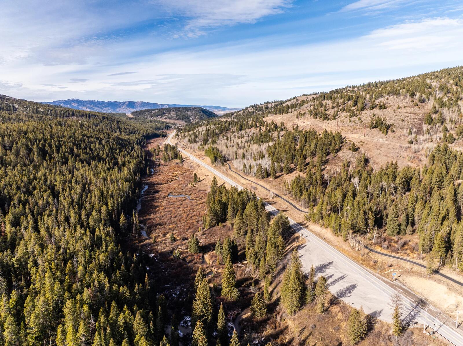 Aerial view of the two-lane mountain highway winding through a forested canyon between Teton Valley and Jackson