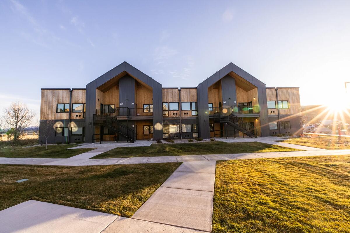 Teton Flats buildings with twin wood-lined gable entries and lawns at golden hour
